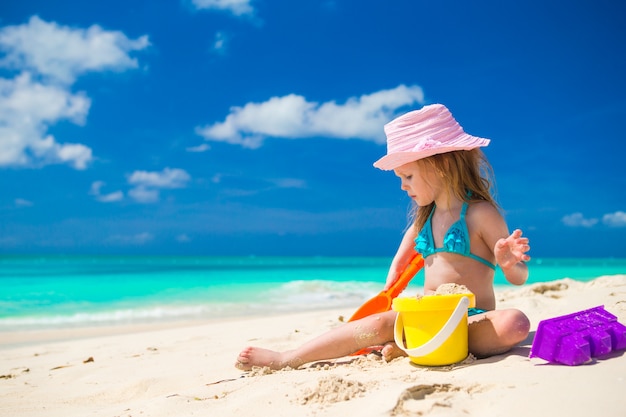 Schattig klein meisje spelen op het strand met wit zand