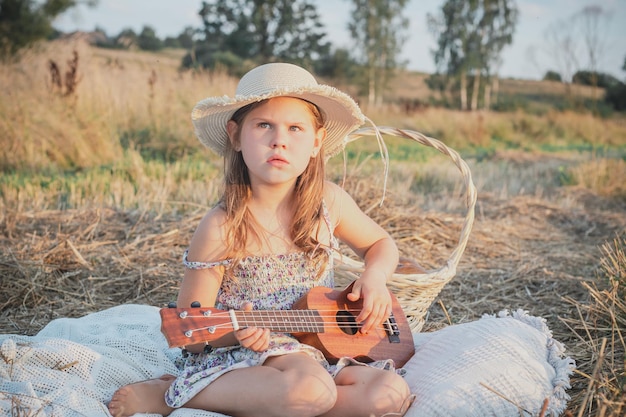 Schattig klein meisje spelen ukelele zittend op deken op veld Portret van kind met ontevreden gezichtsuitdrukking in Panama