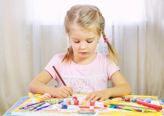 Schattig klein meisje tekent thuis met potloden en viltstiften