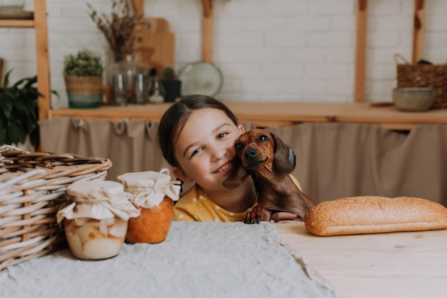 Schattig klein meisje thuis in de keuken bakt koekjes met haar hond teckel