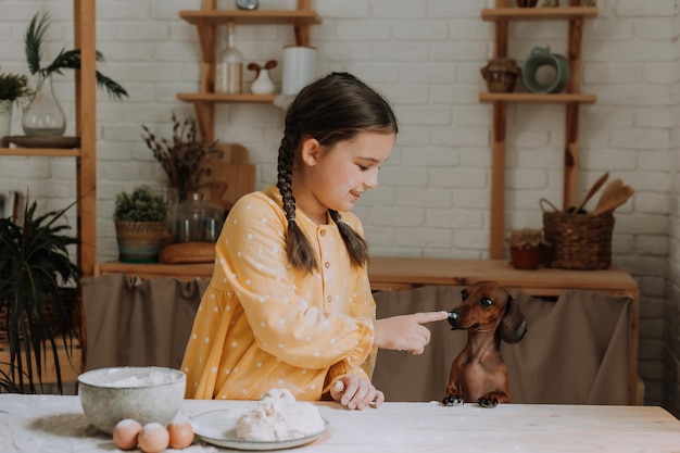 Schattig klein meisje thuis in de keuken bakt koekjes met haar hond teckel