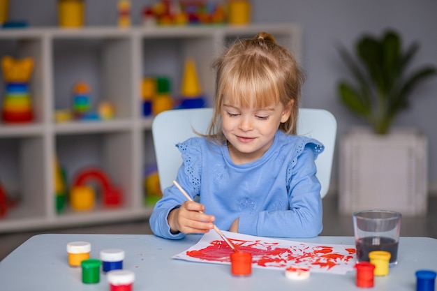 Schattig klein meisje trekt met verf in de kleuterschool