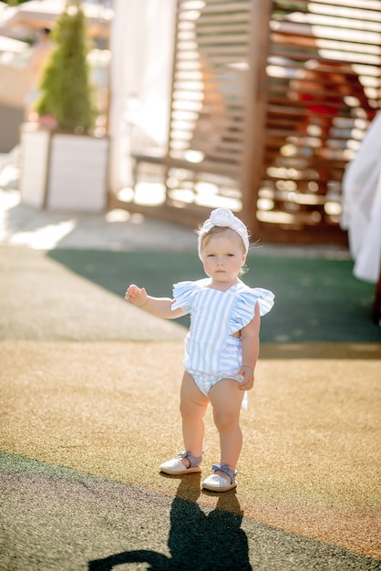 Schattig klein meisje van 1 jaar oud op het strand van het resort in de zomer in een trendy outfit