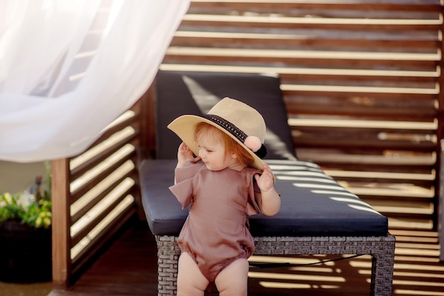 Schattig klein meisje van 1 jaar oud op het strand van het resort in de zomer in een trendy outfit