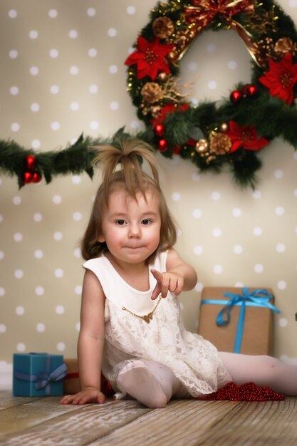 Schattig klein meisje verkleedt kerstboom op de vloer in de kamer