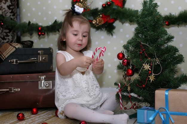 Schattig klein meisje verkleedt kerstboom op de vloer in de kamer