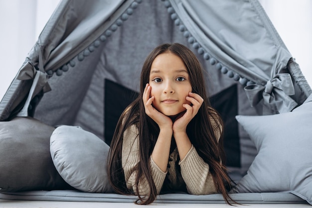 Schattig klein meisje zit in vigvam tent