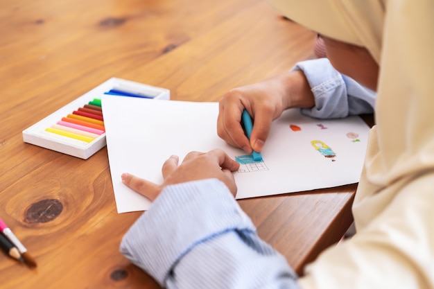 Schattig klein moslim meisje genieten van schilderen op school. Onderwijs, school, kunst en schilderconcept