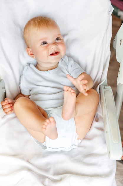 Schattig klein pasgeboren meisje met lachend gezicht camera kijken op witte achtergrond. baby baby rusten spelen liggend op de voedingsstoel thuis. moederschap gelukkig kind concept.