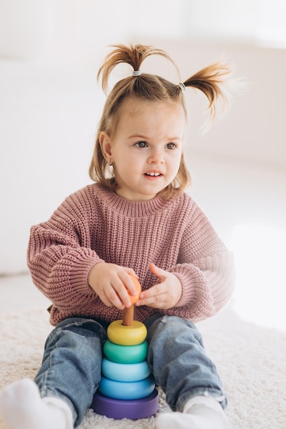 Schattig klein peutermeisje dat thuis speelt met eco houten speelgoed gelukkig kind dat groenten en fruit snijdt met een speelgoedmes het kind dat educatieve spelletjes speelt