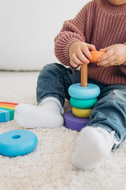 Foto schattig klein peutermeisje dat thuis speelt met eco houten speelgoed gelukkig kind dat groenten en fruit snijdt met een speelgoedmes het kind dat educatieve spelletjes speelt