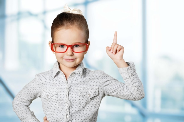 Schattig klein schoolmeisje in glazen op achtergrond