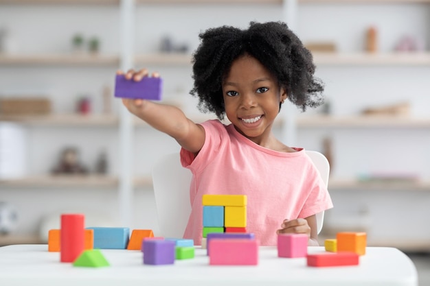 Schattig klein zwart meisje met paars houten blok