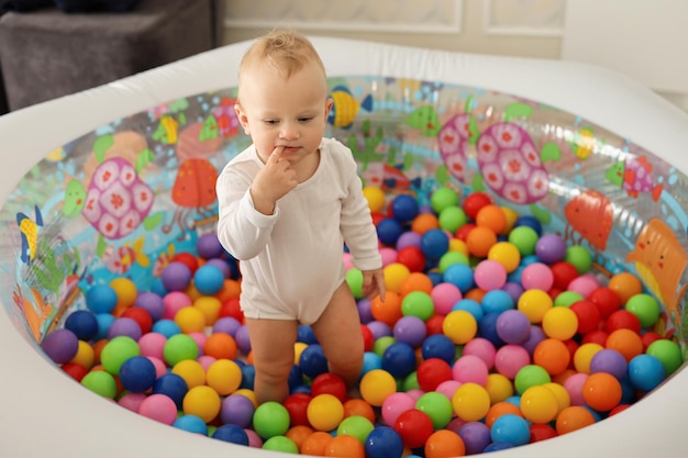 schattig krullend blond kind speelt in een opblaasbaar zwembad met gekleurde ballen