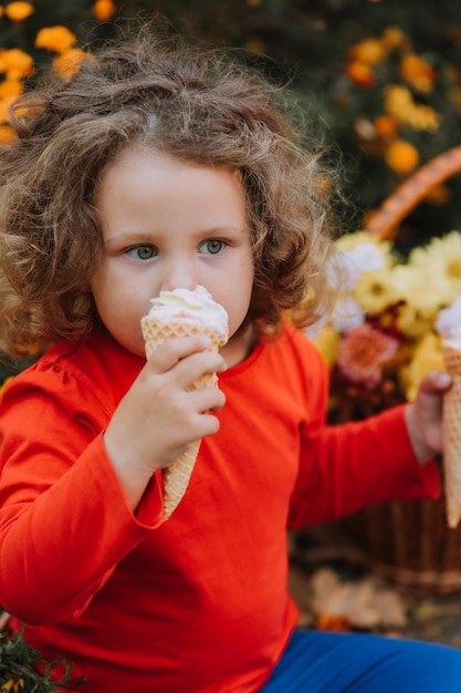 schattig krullend meisje dat ijs eet in de herfst van het park herfstkaart bloemen banner