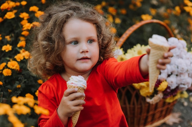 schattig krullend meisje dat ijs eet in de herfst van het park herfstkaart bloemen banner