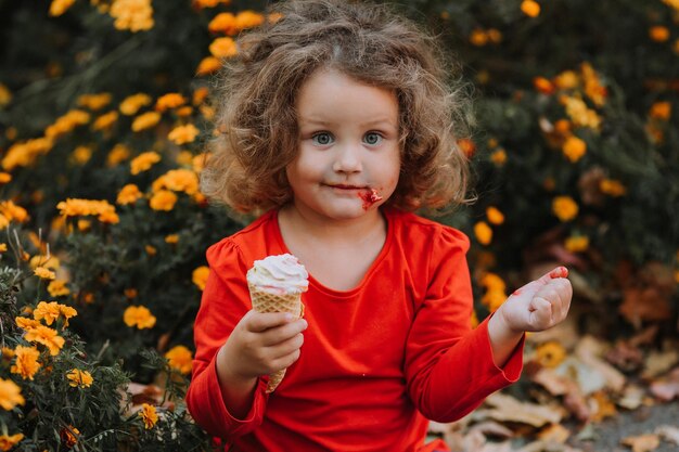 schattig krullend meisje dat ijs eet in de herfst van het park herfstkaart bloemen banner