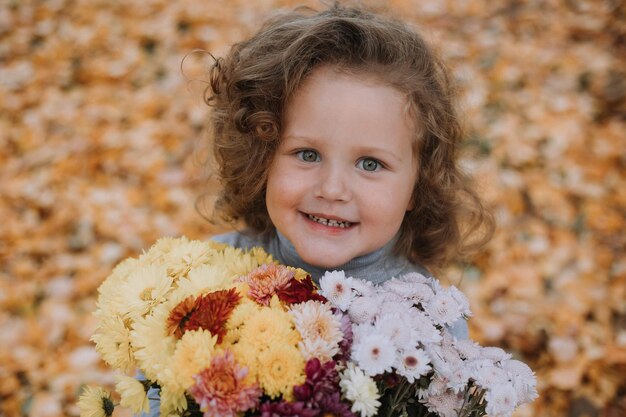 schattig krullend meisje in blauw shirt in park met bloemen in de herfst herfst gezondheidskaart banner