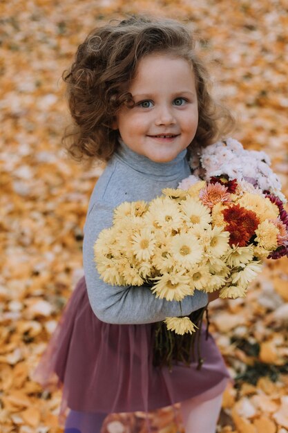 schattig krullend meisje in blauw shirt in park met bloemen in de herfst herfst gezondheidskaart banner