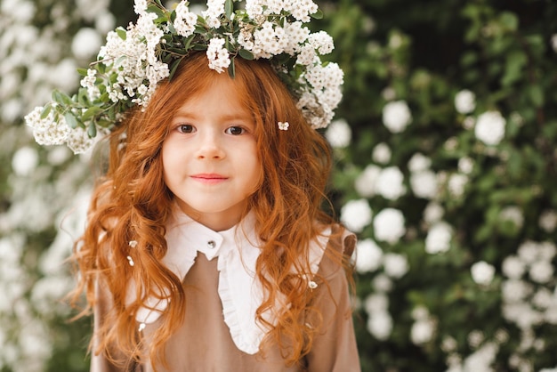 Schattig lachend klein kind meisje 3-4 jaar oud draag bloemenkrans en stijlvolle rustieke jurk over de natuur