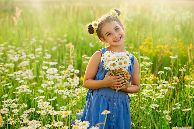 Schattig lachend klein meisje met een boeket madeliefjes staat in een veld met madeliefjes