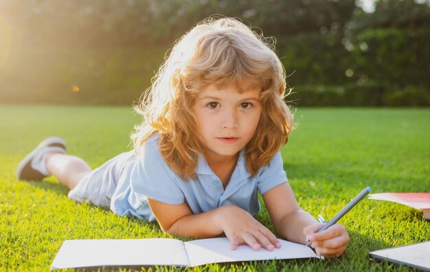 Schattig lief kind met potlood schrijven op notebook buiten kind lees boek in park zomervakantie huis