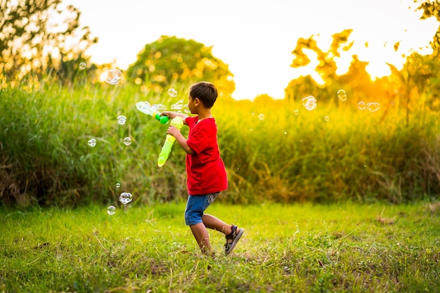 Schattig mannelijk kind vangt zeepbellen in de natuur