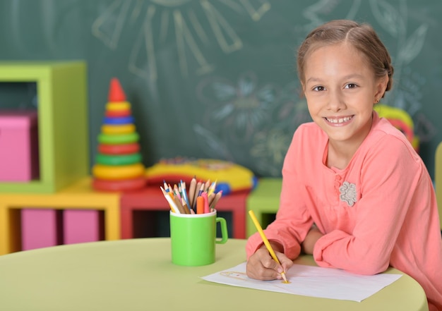 Schattig meisje aan tafel zitten en tekenen met potloden