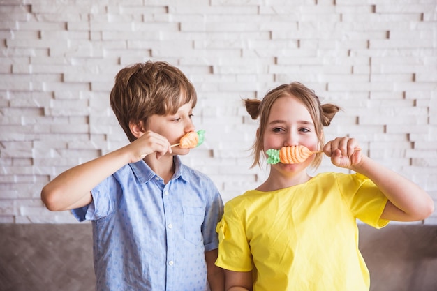 Schattig meisje en jongen houden kleurrijke zoete schuimgebakjes op een stokje op Paasdag