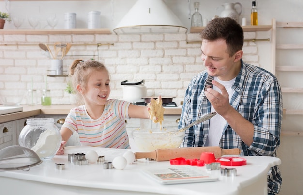 Schattig meisje en vader deeg kneden tijdens het bakken in de keuken thuis, kopieer ruimte