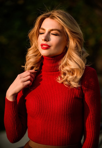 Schattig meisje geniet van de laatste zonnestralen van de zonnige herfst. Modieuze kleding. Vrouwelijkheid en tederheid. Stijlvolle herfstoutfit. Herfstmode. Vrouw lopen in herfst park. Gezellig breiwerk. Gebreide trui.