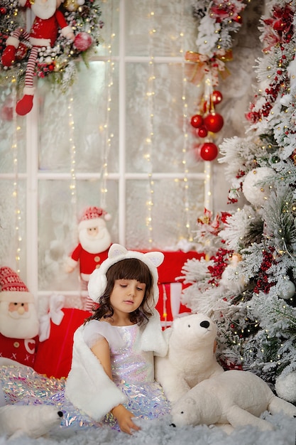 Schattig meisje in afwachting van het nieuwe jaar en kerstmis 2022 in een elegante jurk met cadeaus