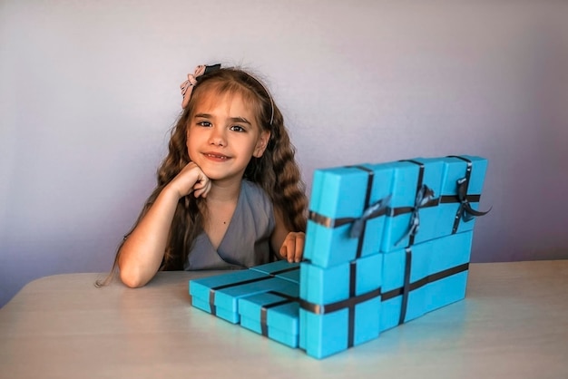 Schattig meisje in de buurt van blauwe geschenkdozen gevormd als laptop