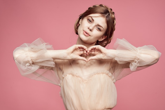 Schattig meisje in een delicate jurk poseren op een roze achtergrond en glimlachen