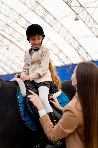 Schattig meisje leren paardrijden Kid in helm op paardrijden