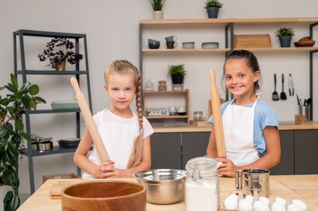 Schattig meisje met schort met brede glimlach tijdens het kijken naar kook-tv-show op digitale tablet om smakelijke salade voor haar familie te bereiden, portretschot