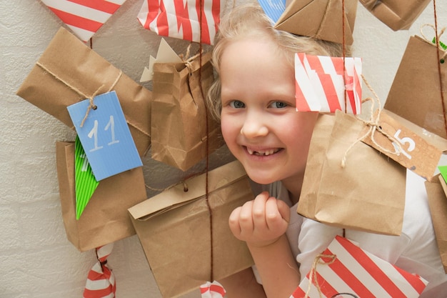 Schattig meisje met verloren melktanden spelend met een anventkalender die aan de muur hangt