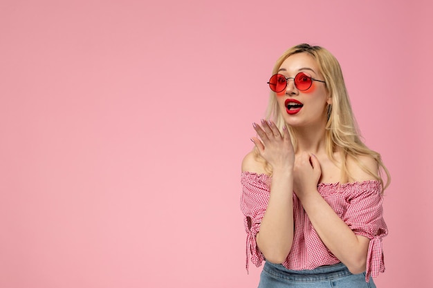 Schattig meisje mooie jonge dame met rode bril in roze blouse geschokt iets te zien