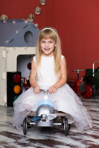 Schattig meisje speelt met speelgoedauto's. Rijdt op een speelgoedmachine met typemachine.