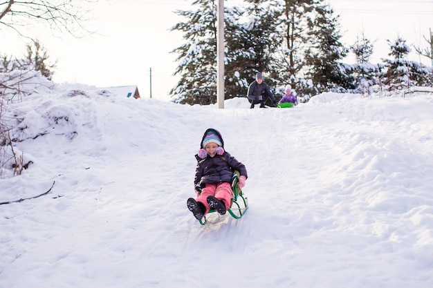 Schattig meisje trekt een slee in warme winterdag