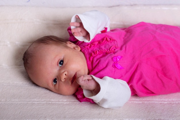 Schattig meisje van een maand oud in roze jurk ligt op een zachte deken