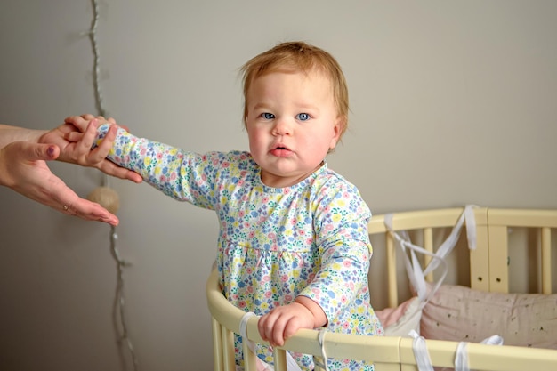 Schattig meisje van tien maanden oud speelt alleen thuis in een wiegje 's middags of' s ochtends