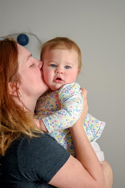 Schattig meisje van tien maanden oud speelt in de armen van haar moeder Gelukkige jeugd