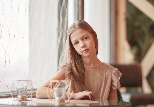 Schattig meisje zit aan een tafel in een café