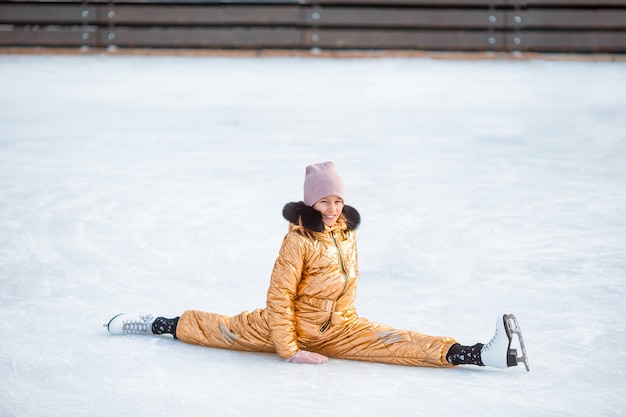 Schattig meisje zittend op ijs met schaatsen na de herfst