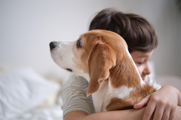 Schattig moment vastgelegd van een jonge jongen die zijn geliefde beagle omhelst met gesloten ogen van pure vreugde