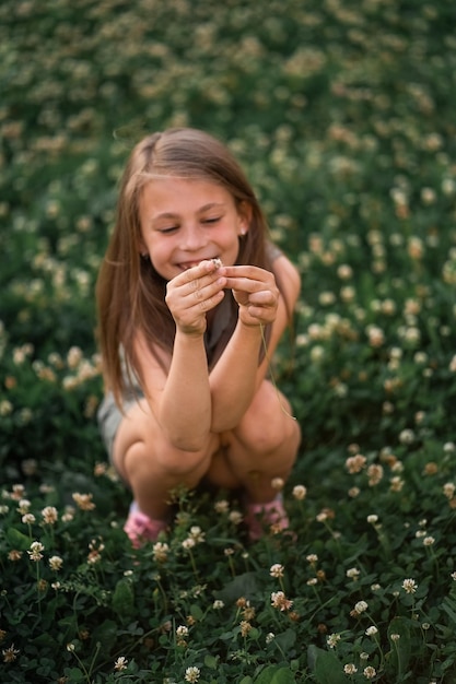 Schattig mooi klein meisje op een achtergrond van groen gras verzamelt bloemen