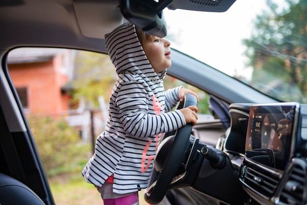 schattig peutermeisje dat een moderne auto bestuurt.