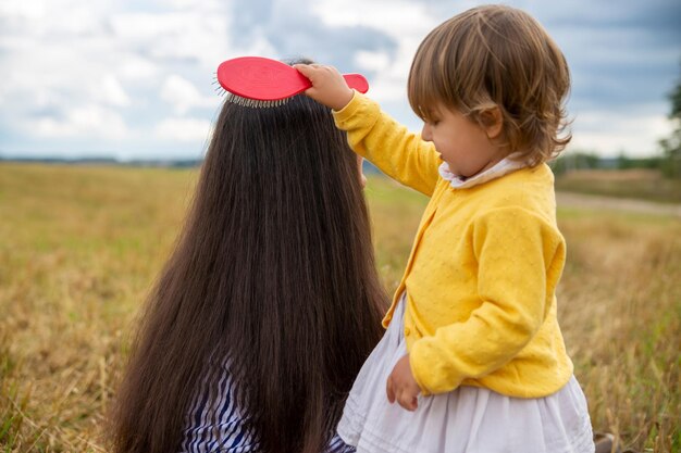 Schattig peutermeisje dat haar moeders haar buiten op een zonnige dag buiten kamt