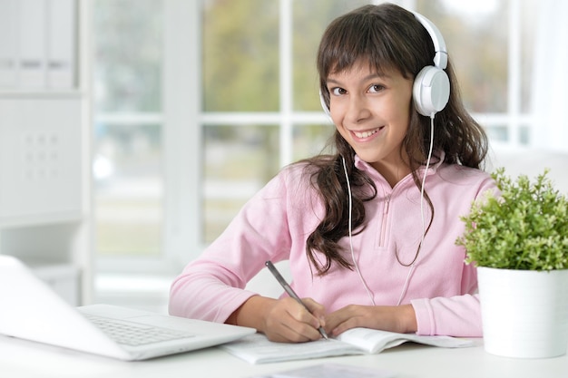 Schattig tienermeisje zittend aan tafel met laptop en huiswerk